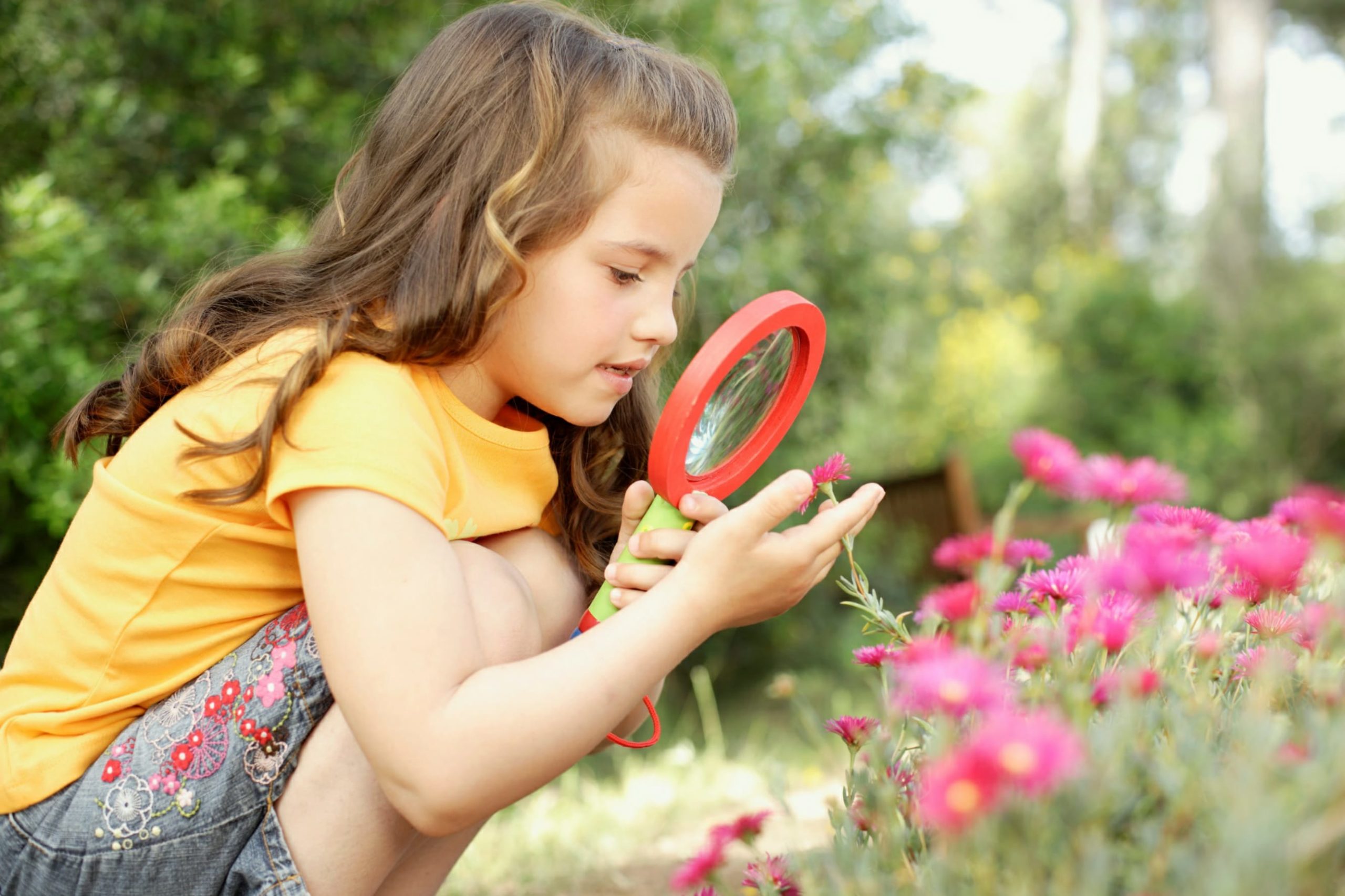 Girl looking at flowers through a magnifying glass