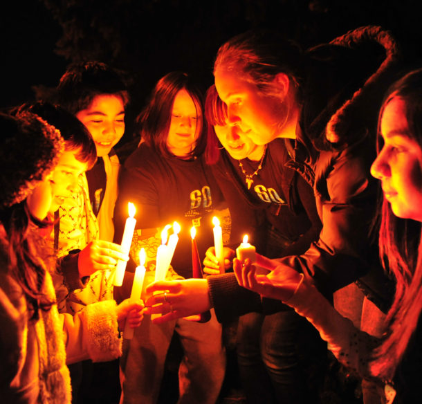 Students light candles in dark for earth hour