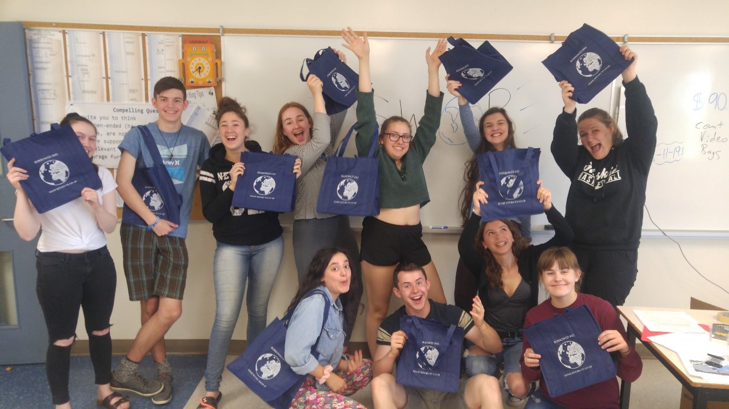 Students from Cape Breton Highlands pose together in a classroom, holding the reusable grocery bags they designed for this project.