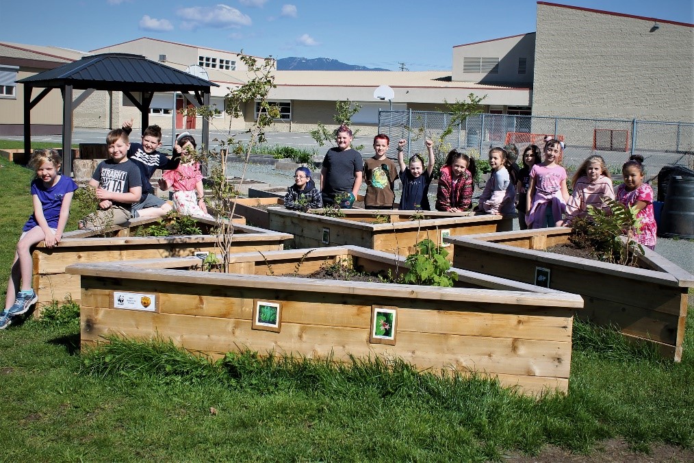 Students gather around the new native garden boxes planted on their school grounds at Vedder Elementary